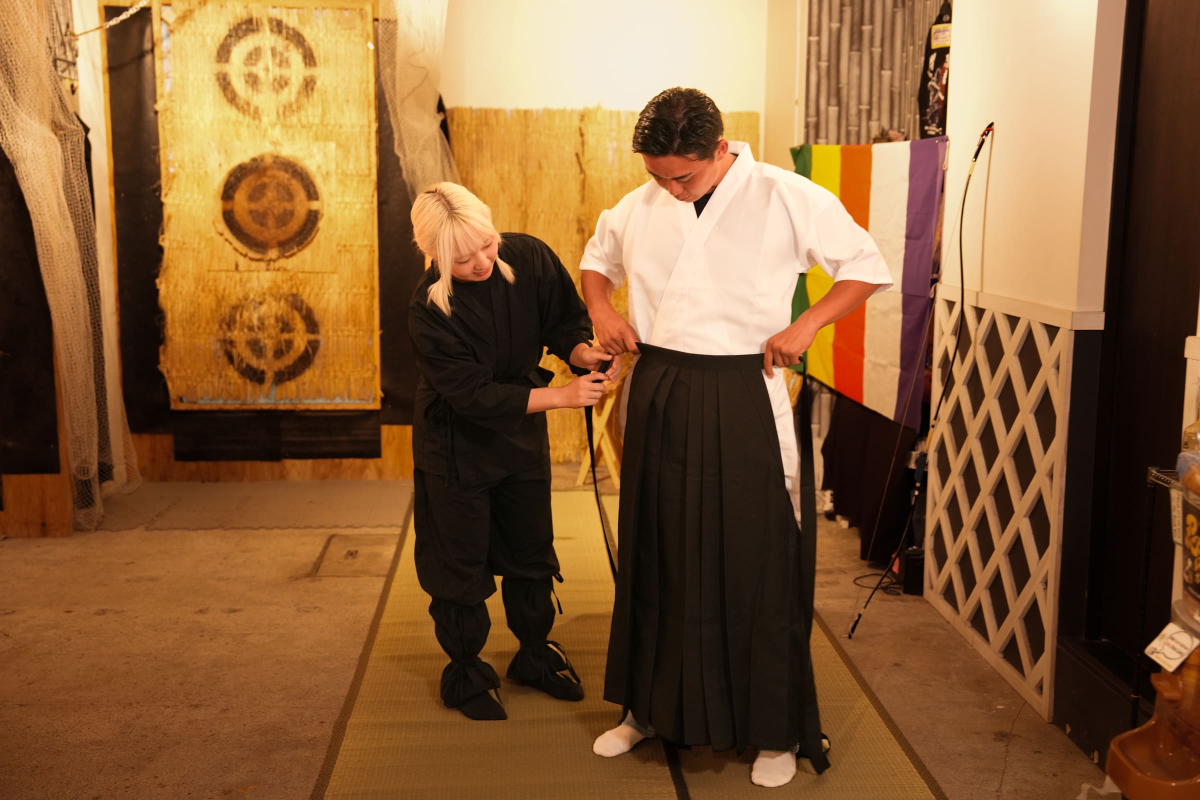 Guest in white keikogi and black hakama being dressed by staff before a kyudo Japanese archery session